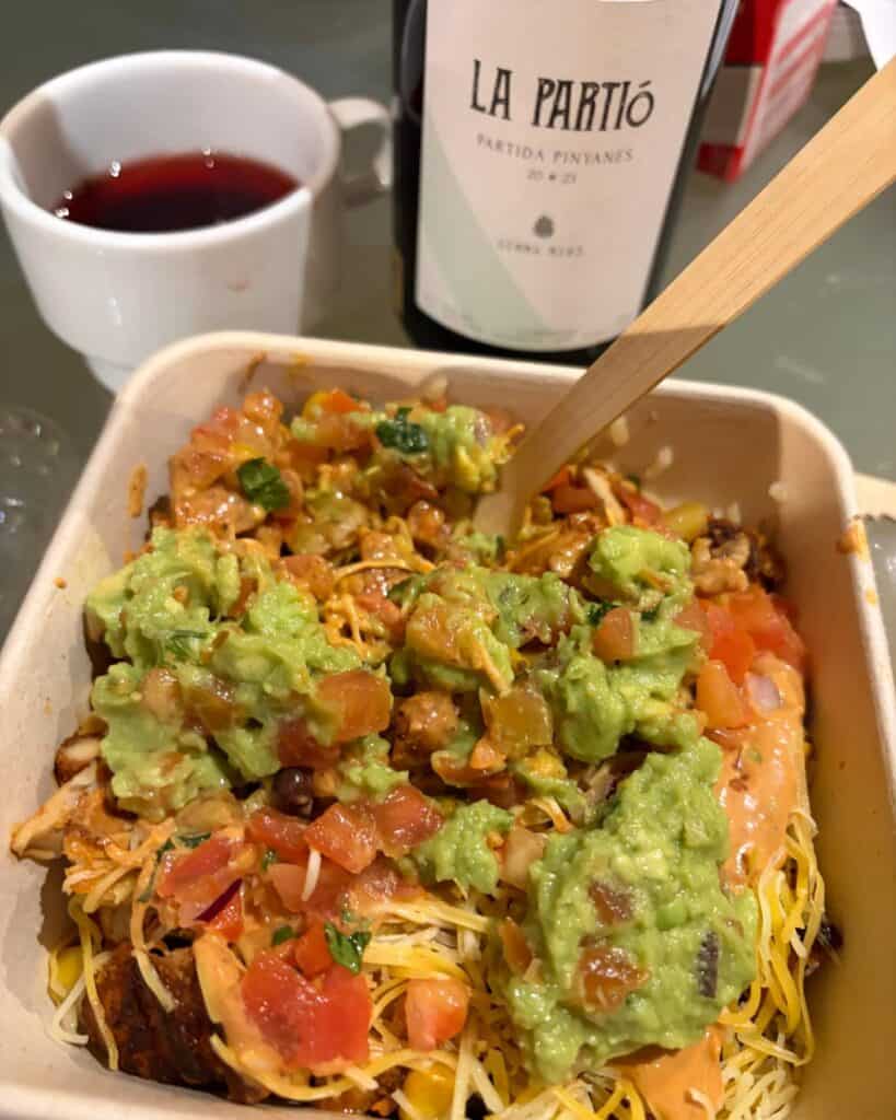 A burrito bowl paired with a red wine poured into a coffee cup.