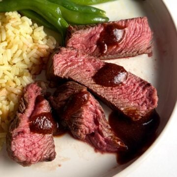 Denver steak slides served with BBQ sauce, rice and green beans.