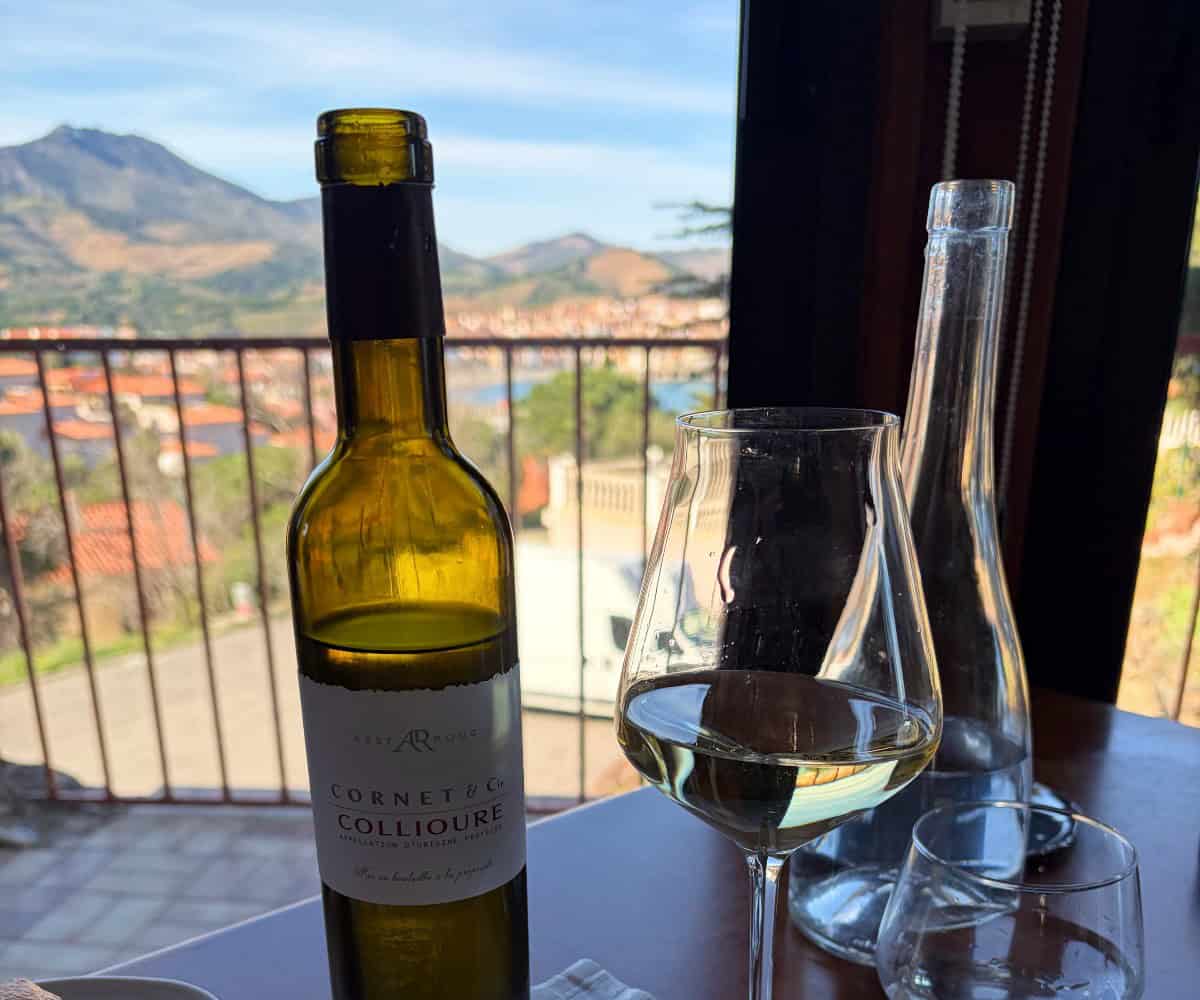 bottle of wine in front of a restaurant window, with a view of Banyuls-sur-Mer.