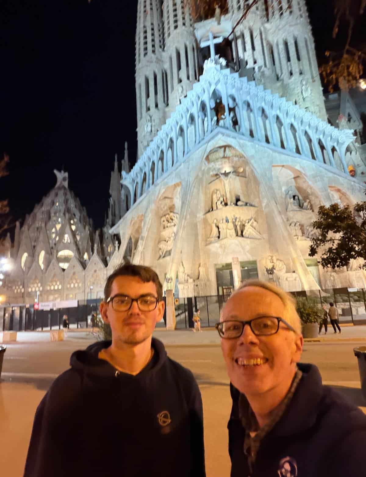 Father and son posing in front of Sagrada Familia at night, in Barcelona, Spain.