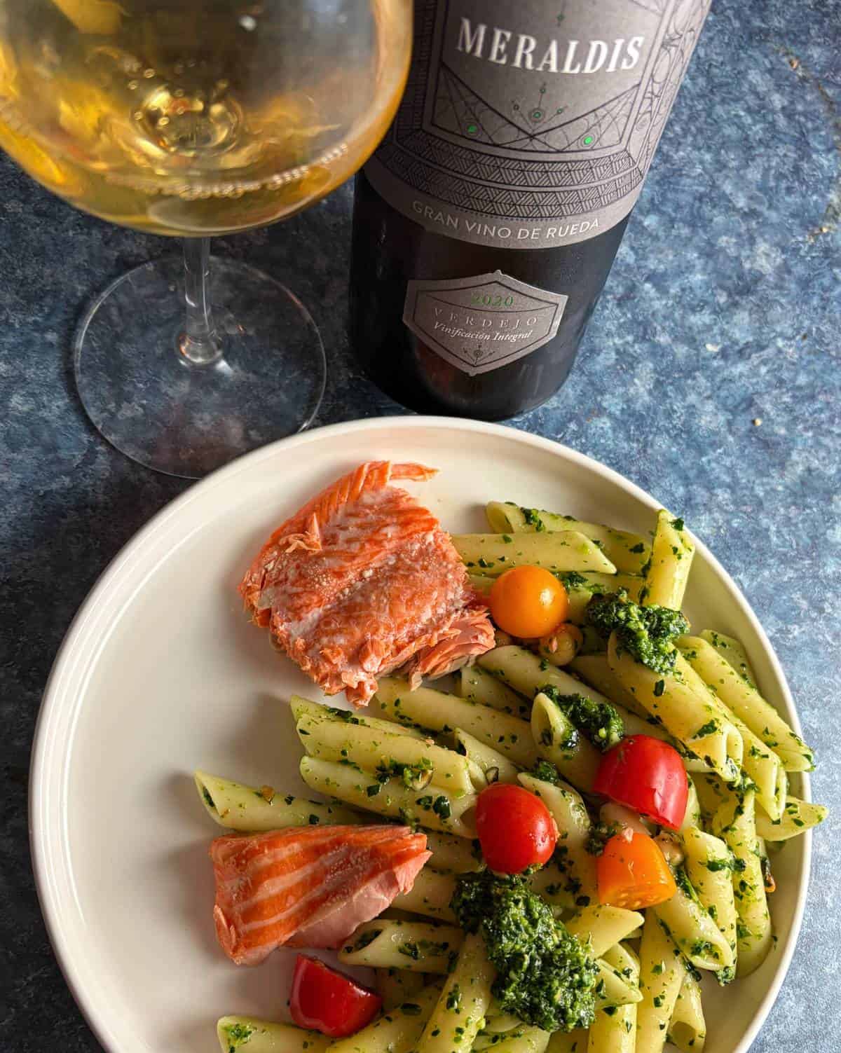 salmon served alongside ziti with pesto sauce, and a white Verdejo wine.