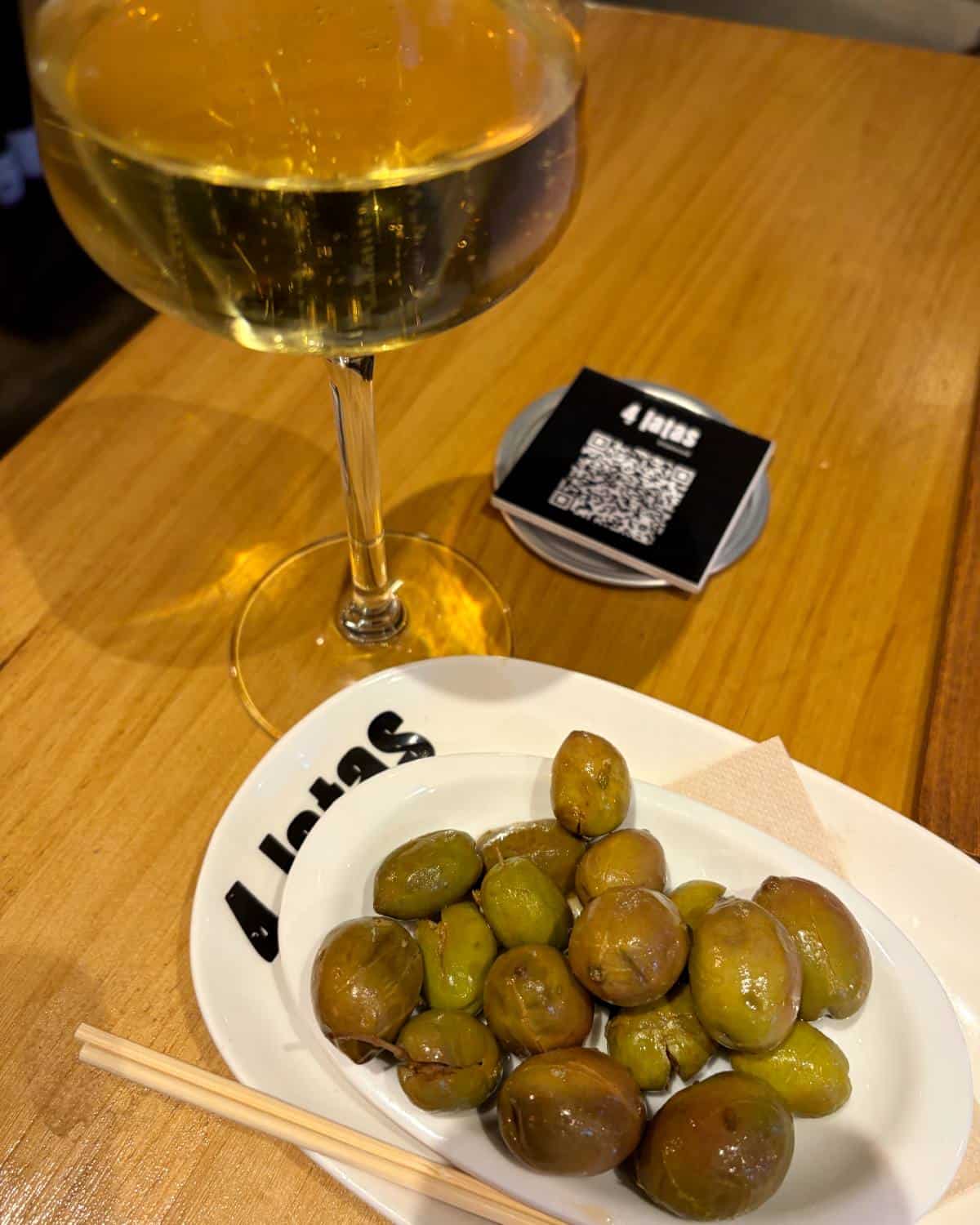 glass of cava with olives alongside it.